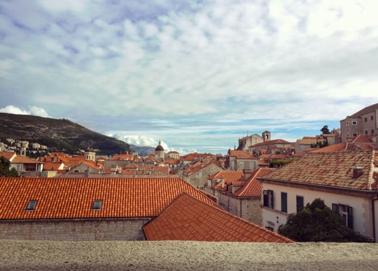 brown and white concrete houses under white clouds during daytime