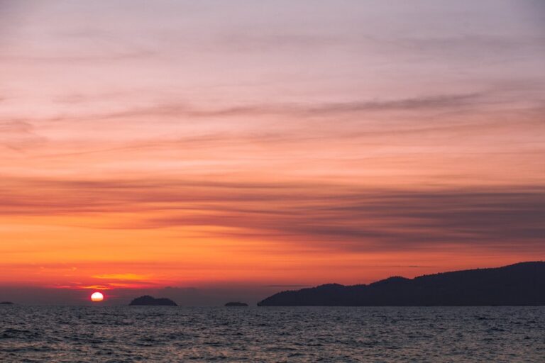 a sunset over a body of water with mountains in the background