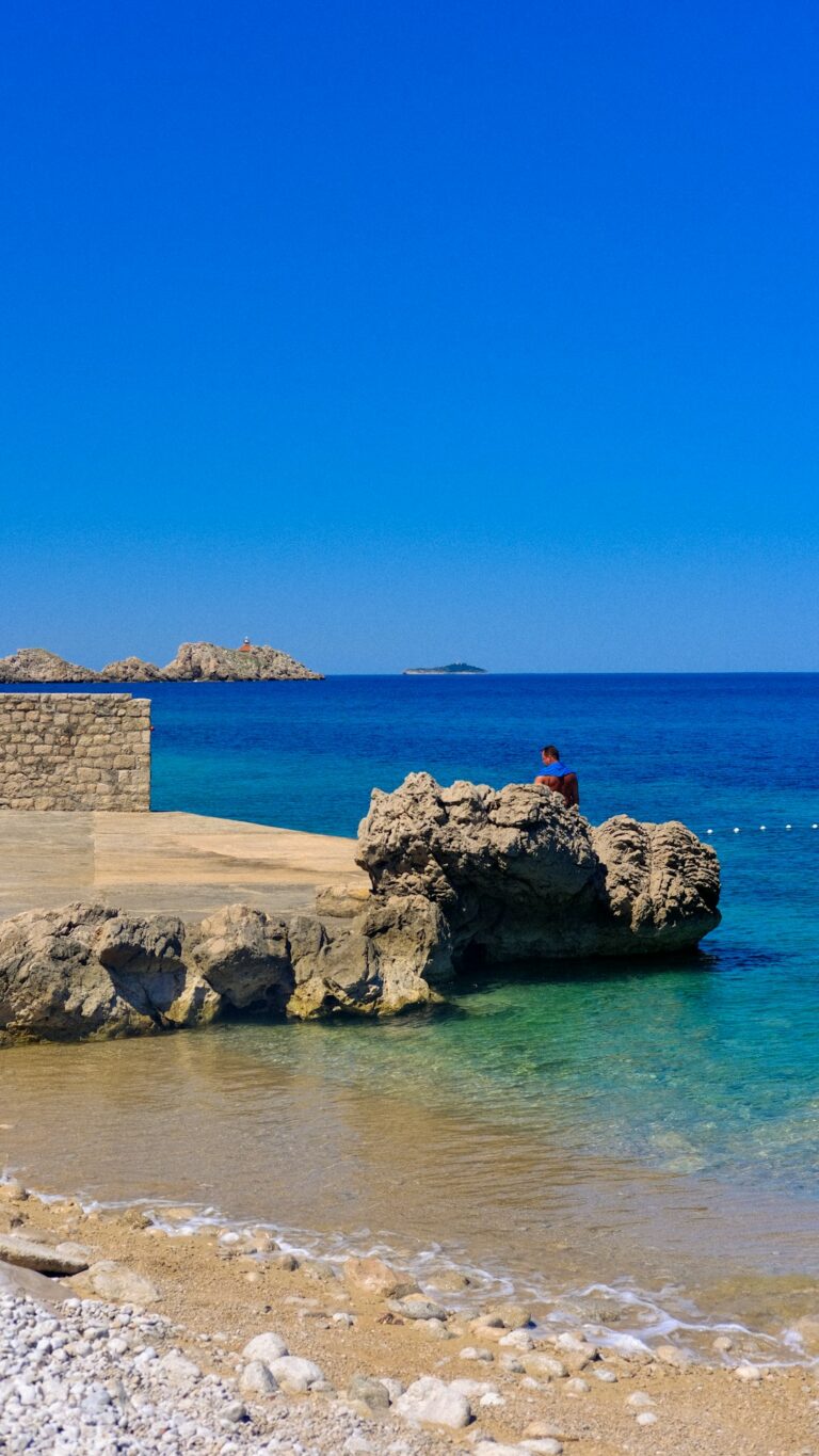 a person sitting on a rock in the ocean