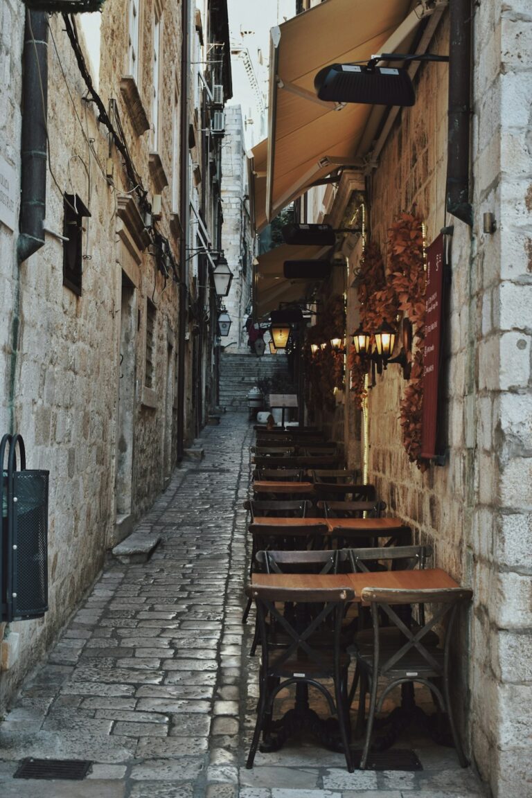 a narrow alleyway with tables and umbrellas