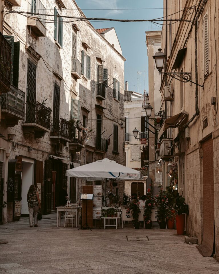 an alleyway with tables and chairs and a white umbrella