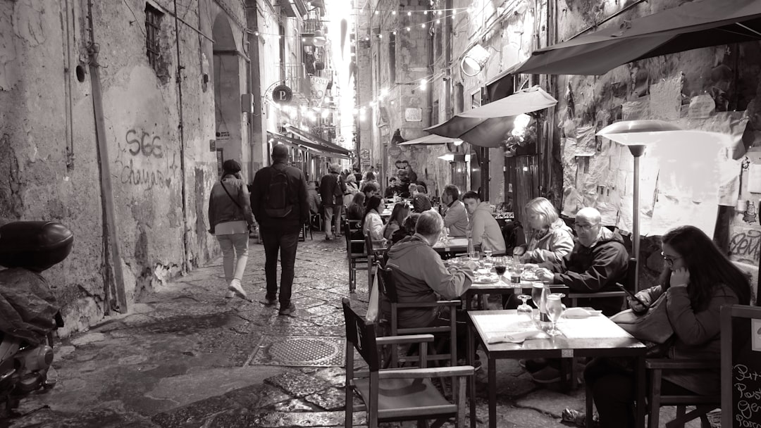 a group of people sitting at tables in a narrow alleyway